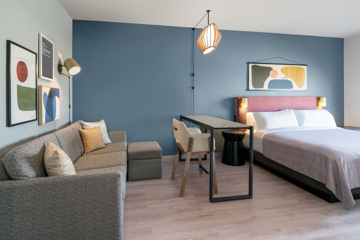 Een moderne slaapkamer met een bed, een bureau, een bank en een stoel.