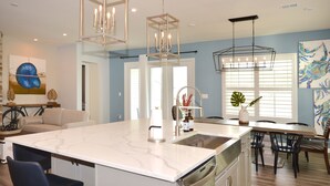 A modern kitchen with a marble island, stainless steel appliances, and pendant lighting.