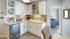 Una cocina con gabinetes blancos, un refrigerador de vinos empotrado y un salpicadero de azulejos.