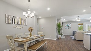 A dining area with a wooden table and chairs, a chandelier, and artwork on the walls. - New Modern Home, Lakefront, Park & Pool, spacious 4br/3ba very safe place<br> (Baton Rouge)