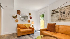 A living room with two leather sofas, a round mirror, and decorative wall art. - "Calm it Down" Bikes, Beach, and 5 star reviews! (Kitty Hawk)