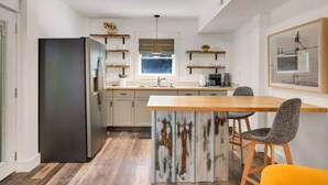 A modern kitchen with a central island, a refrigerator, and bar stools. - "Calm it Down" Bikes, Beach, and 5 star reviews! (Kitty Hawk)