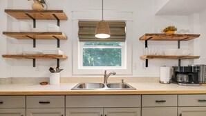 A kitchen with wooden shelves, a double sink, and cabinets. - "Calm it Down" Bikes, Beach, and 5 star reviews! (Kitty Hawk)