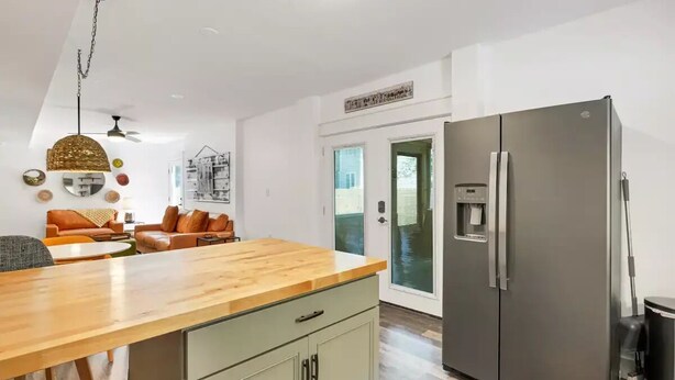 A modern kitchen with a large refrigerator, wooden countertop, and a dining area with a sofa and table. - "Calm it Down" Bikes, Beach, and 5 star reviews! (Kitty Hawk)