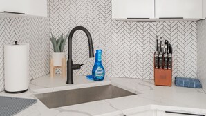 Une cuisine avec un dosseret de carreaux disposés en motif chevron, un robinet noir, une bouteille de produit vaisselle Dawn Powerwash et un bloc à couteaux.