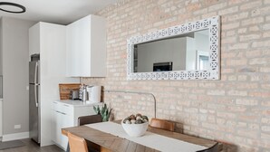 Une cuisine moderne avec des meubles blancs, un mur en briques et un miroir décoratif.