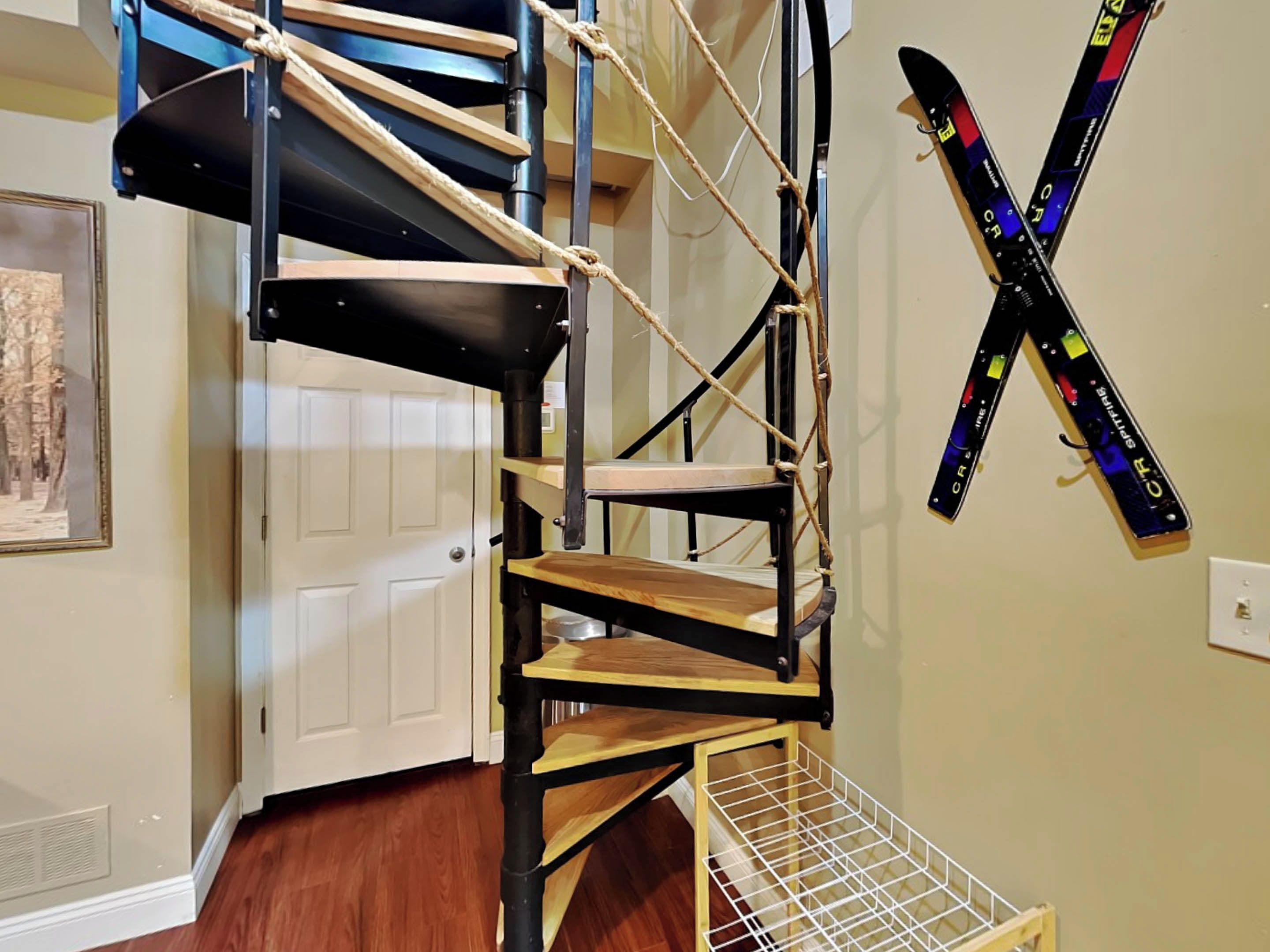 A spiral staircase with wooden steps and metal railings, leading to an upper floor.