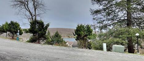 A gravel driveway leading to a house with a view of a lake and trees.