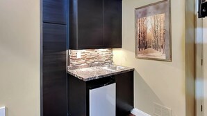 A compact kitchen with dark cabinetry, a tiled backsplash, and a sink. - Loft of Luxury by Taylor Made Deep Creek (Oakland)