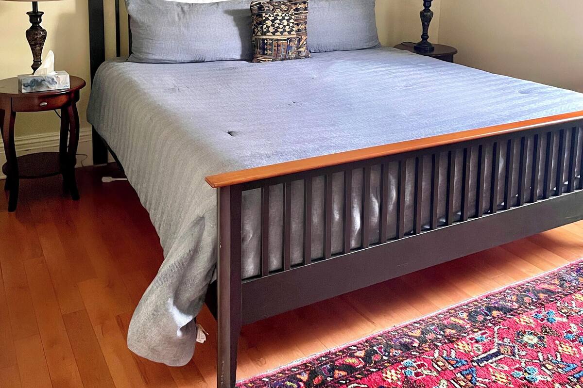 Un dormitorio con una cama, dos mesitas de noche y un cuadro grande sobre la cama.