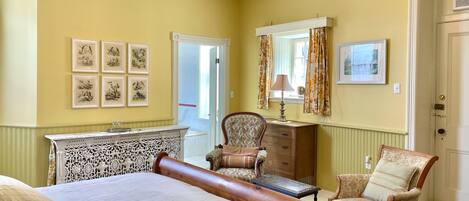A bedroom with a large bed, a wooden headboard, a chair, a dresser, and a chandelier.
