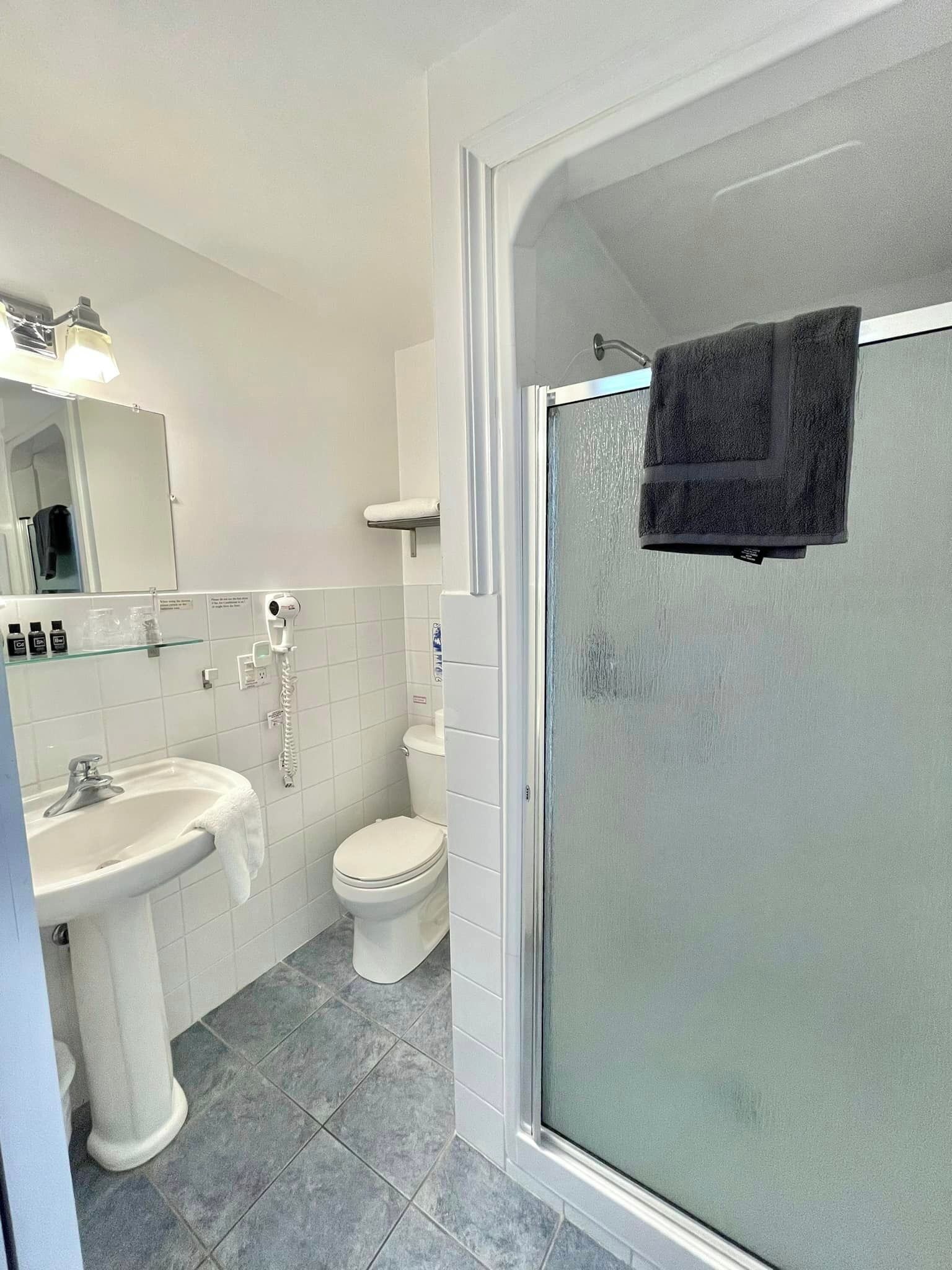 Un baño moderno con ducha de vidrio, un lavabo blanco y un inodoro.