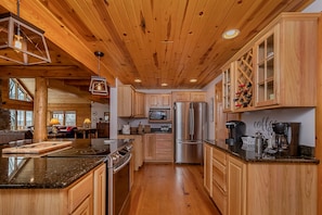 Enjoy cooking in this well-equipped kitchen with a large island, sink, stove, and coffee station.