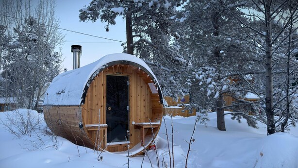 Een houten hut met een sneeuwbedekte dak, omringd door sneeuwzware bomen.
