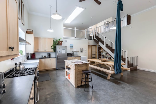 A spacious kitchen with a central island, a dining area with a bench, and a staircase leading to an upper level.