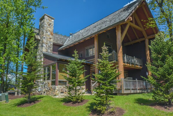A lodge with a stone chimney, wooden beams, and a balcony. - Retreat on Main Street by Taylor Made Deep Creek (McHenry)