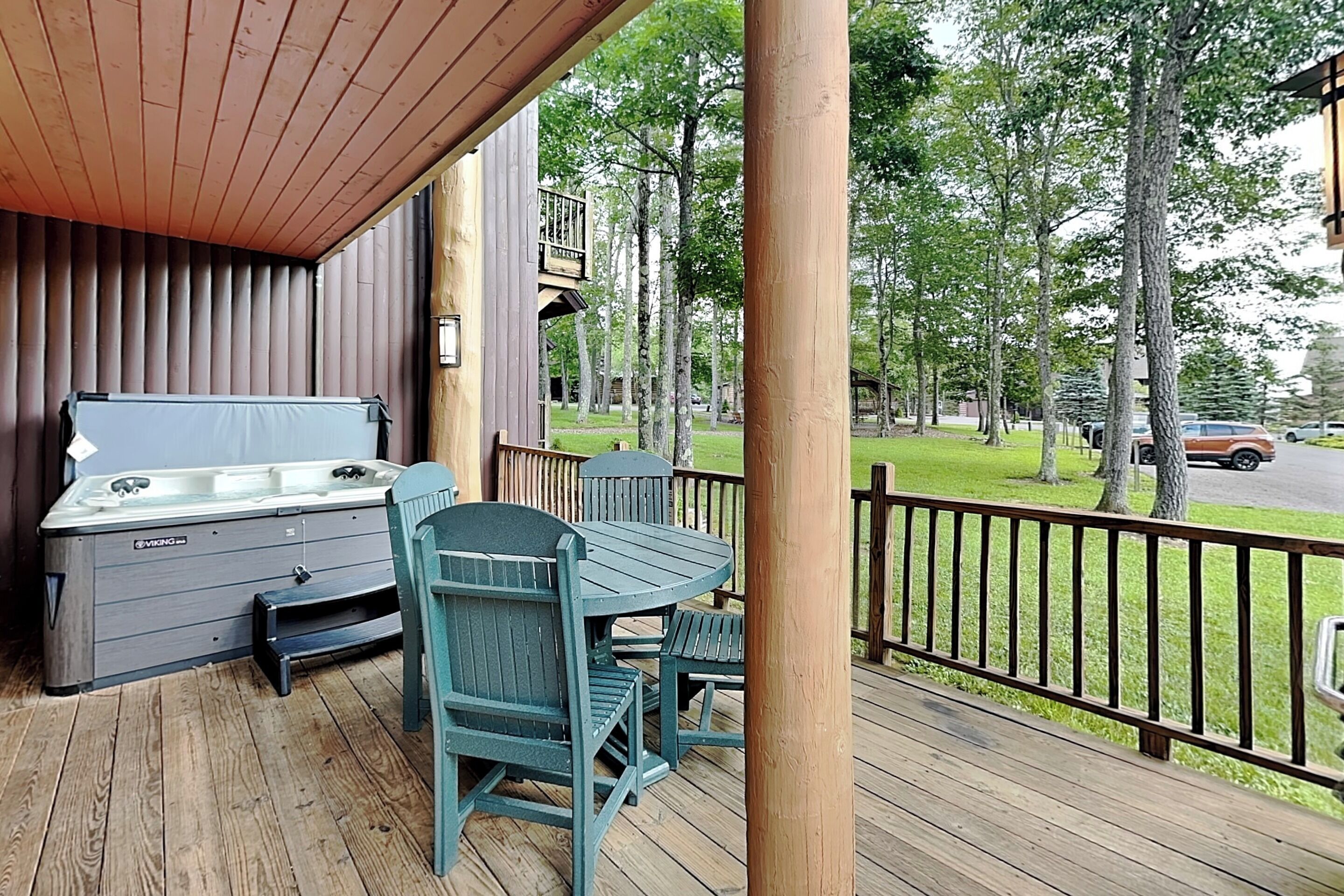 Une terrasse en bois avec un jacuzzi, deux chaises et une table.