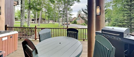 A covered outdoor area with a grill, hot tub, and seating.