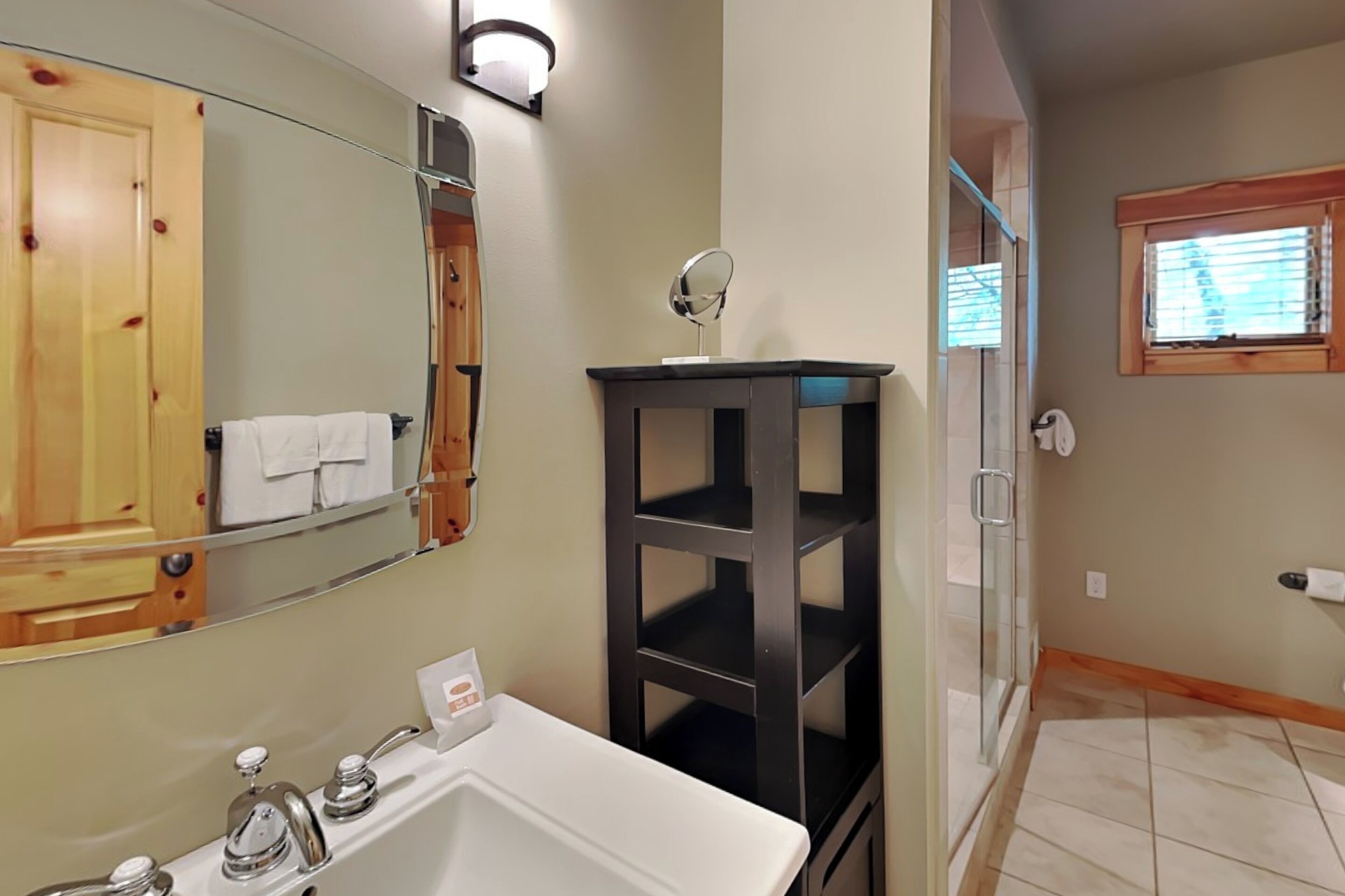 A bathroom with a white sink, a mirror, a towel rack, and a wooden cabinet.