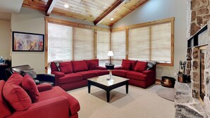 A living room with red sofas, a coffee table, and a stone fireplace. - Retreat on Main Street by Taylor Made Deep Creek (McHenry)