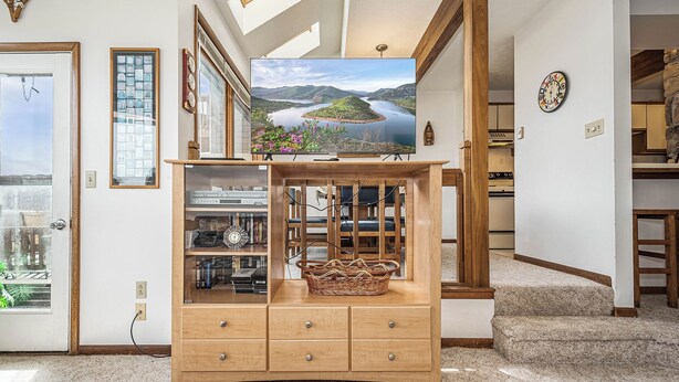 Un salon avec un meuble en bois, un téléviseur posé sur un meuble, et une vue sur un lac par la fenêtre.