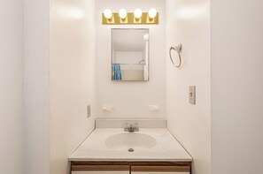 A bathroom with a white sink, a mirror with a gold light strip, and a towel rack.