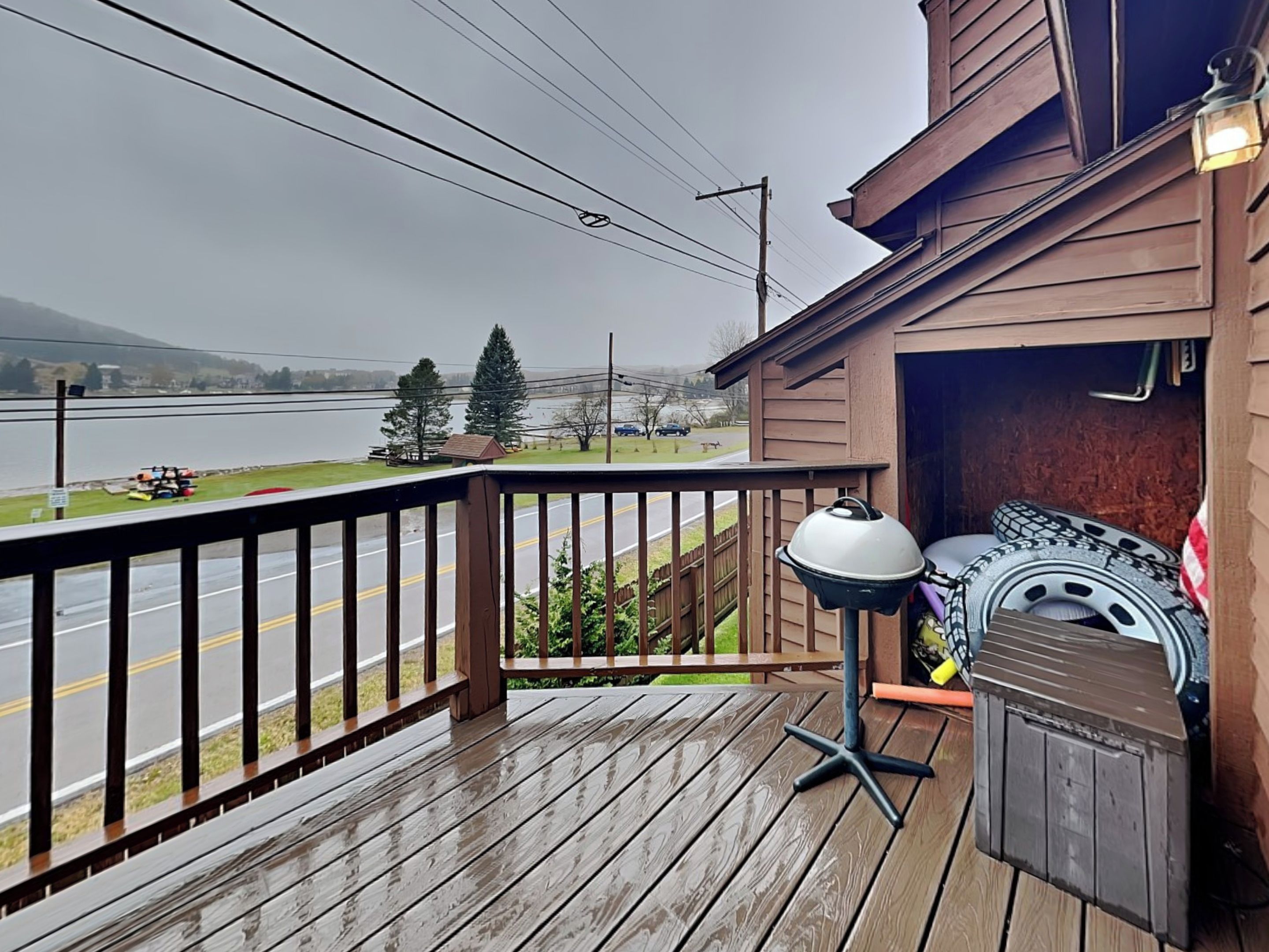 A wooden deck with a railing, a barbecue grill, and a tire swing.