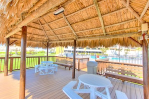 Relax in a shaded outdoor space with picnic tables and benches, surrounded by a secure railing and a nearby swimming pool.