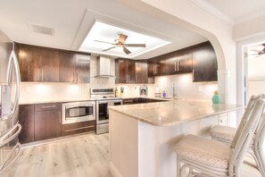 Enjoy cooking in this well-lit kitchen with a central island and seating, stainless steel appliances, and a skylight.