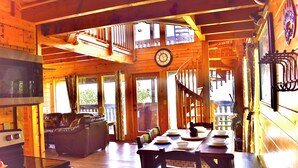 A wooden cabin interior with a dining area, a staircase, and a clock on the wall. - ENCHANTED VIEW~**Super cozy & Awesome Valley Views~10 minutes to Pigeon Forge ** (Sevierville)