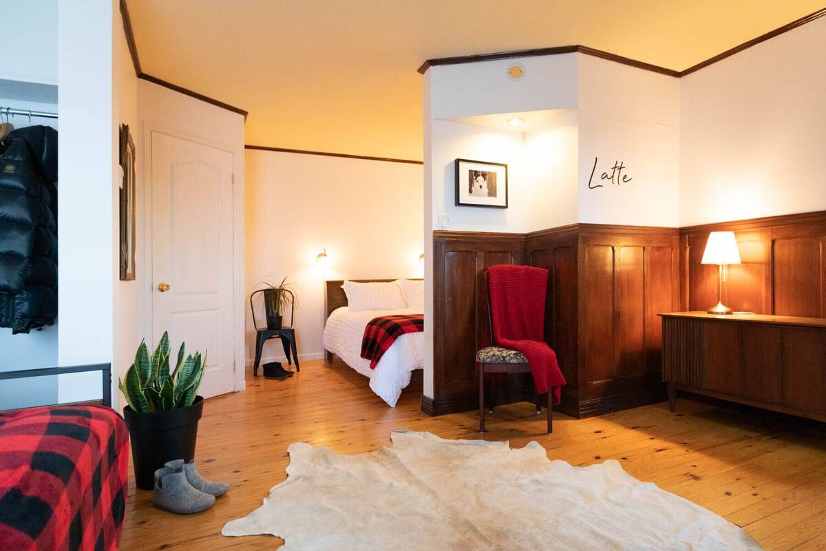 A cozy room with a bed, a chair, a desk, and a large rug.