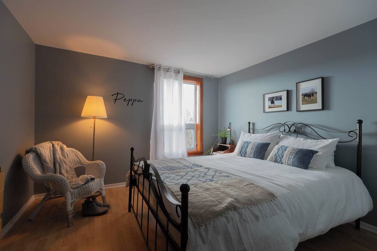 A bedroom with a bed, a chair, a lamp, and a window.