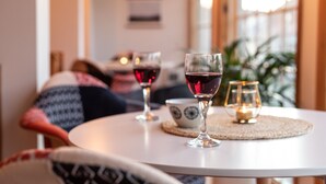 A round table with three wine glasses and a candle, set in a cozy room with a couch and a plant in the background. - Auberge et Campagne (Saint Ferreol les Neiges)