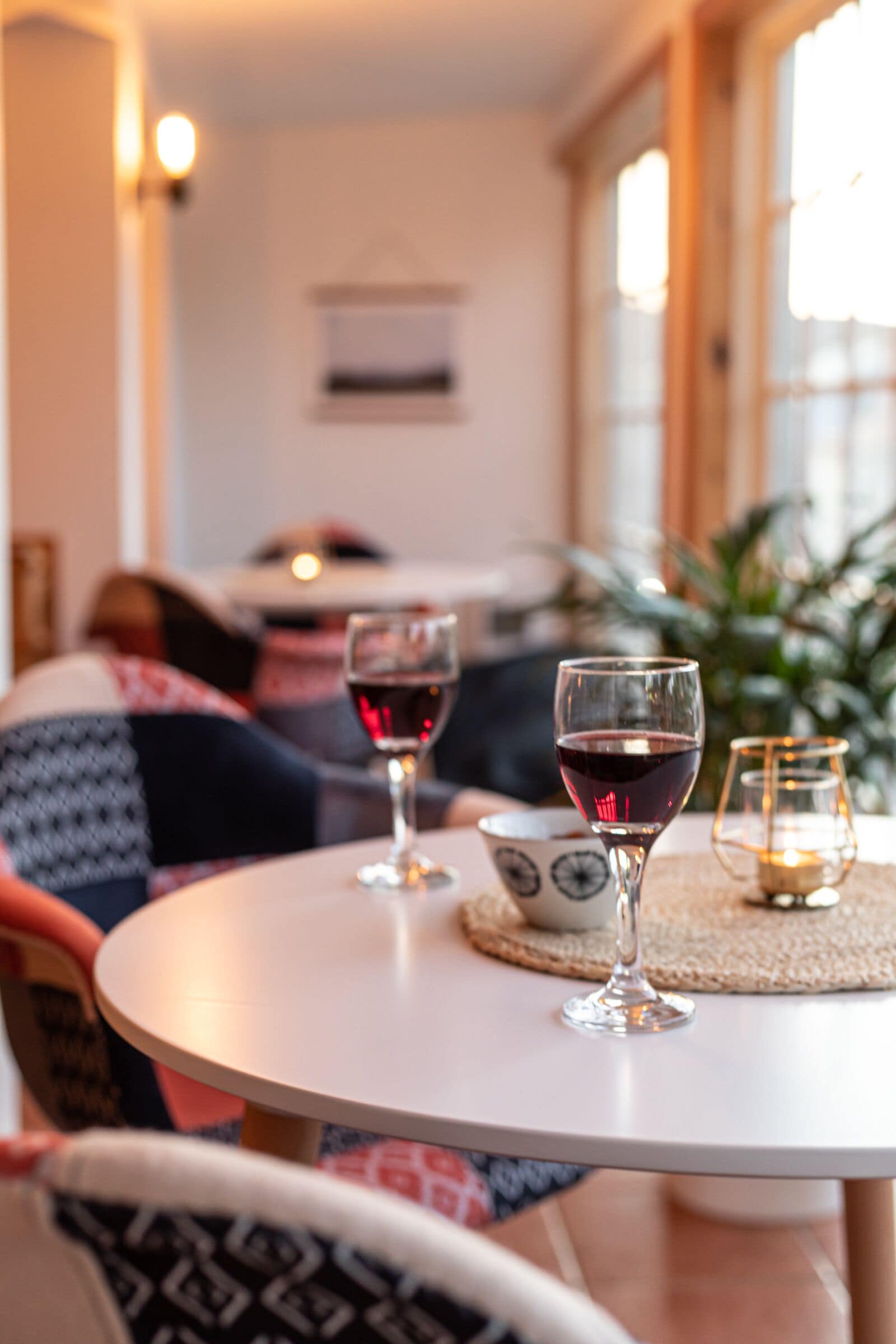 Un rincón acogedor con una mesa redonda, dos copas de vino y un candelabro decorativo.