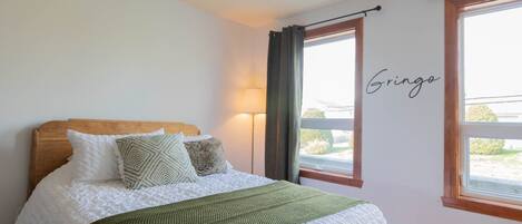 A bedroom with a wooden headboard, a green throw blanket, and a white quilted bedspread.