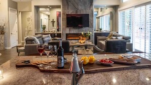 A modern living room with a fireplace, a large TV, and seating areas.