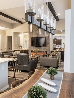 A modern living room with a fireplace, a flat-screen TV, and a dining area with a wooden table and chairs.
