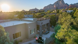 A modern house with a patio, a barbecue area, and a view of mountains.