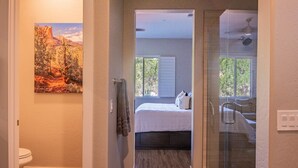 A bathroom with a shower, toilet, and a painting on the wall.