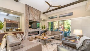 A modern living room with a fireplace, leather sofas, a coffee table, and a TV mounted on a stone wall.