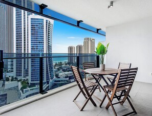 Un balcon avec vue sur la ville, une table avec des chaises et une plante en pot.