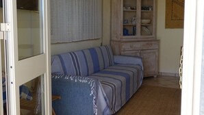 Ein Wohnzimmer mit einem gestreiften Sofa, einem Schrank und einem Fliesenboden.