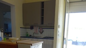Eine Küche mit Kühlschrank, Spüle und einer gefliesten Spritzschutzwand.