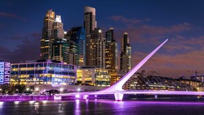 Un moderno horizonte urbano con edificios iluminados y un puente distintivo con estructura de cables blancos.