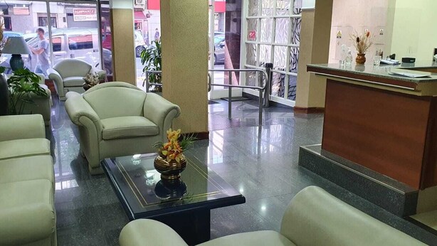 Vestíbulo de hotel con mostrador de recepción, zona de estar y vistas a la calle.