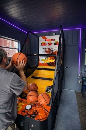 Un jeu d’arcade de basketball avec un tableau de pointage, un panier de basketball et plusieurs ballons de basketball.