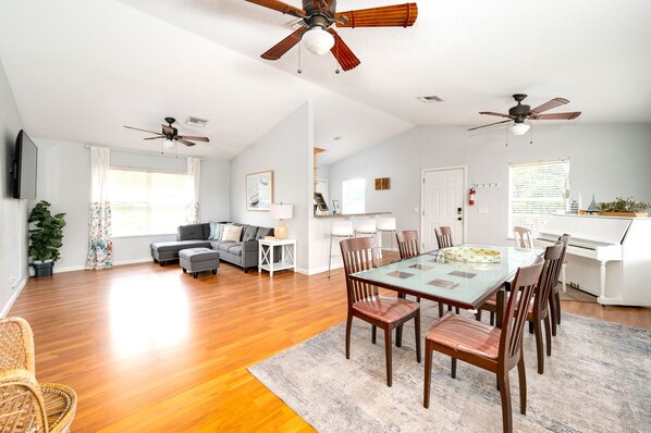 A spacious living area with a dining table, chairs, and ceiling fans.