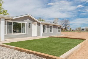 A single-story house with a well-maintained lawn and a gravel driveway. - Green Acres: Stylish Grill & Chill (Fruita)