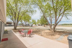 An outdoor patio with a table and chairs, surrounded by trees. - Green Acres: Stylish Grill & Chill (Fruita)
