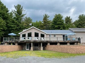 A two-story building with a balcony, outdoor seating, and a stone retaining wall. - Stunning home 17 acres in the Catskill Mountains (Ashland)